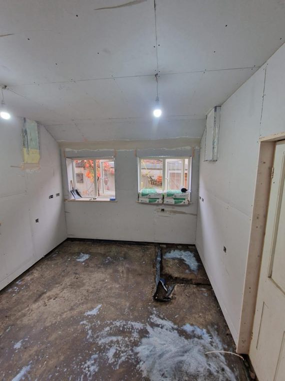 The same room stripped back to bare walls before the kitchen was fitted